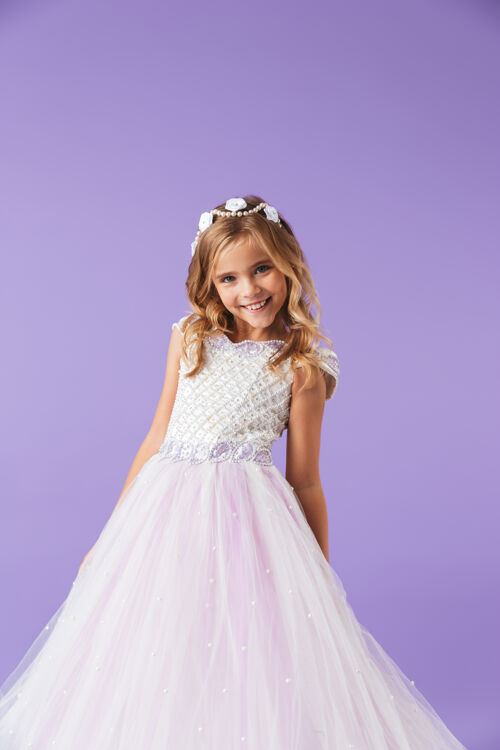 优雅一个微笑愉快的美丽女孩的画像 穿着公主裙 隔着紫罗兰色的墙壁 跳舞微笑白种人年轻