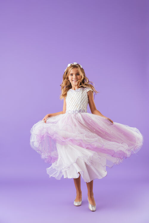 优雅一个微笑愉快的美丽女孩身着公主裙 在紫罗兰色的墙壁上跳舞的全长肖像小舞蹈孩子