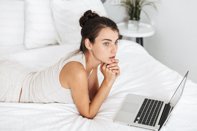 活动美丽的年轻女子在家里的床上休息 使用笔记本电脑休闲连接卧室