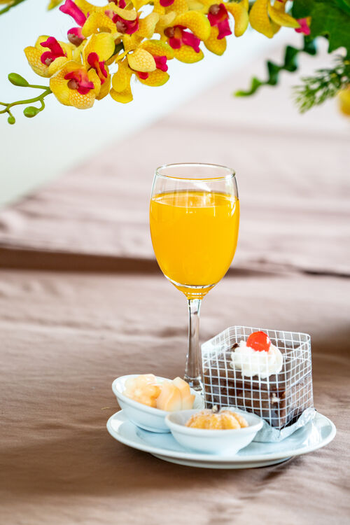 面包香槟杯里的橙汁 旁边有蛋糕和百吉饼霜冻杯子顶部