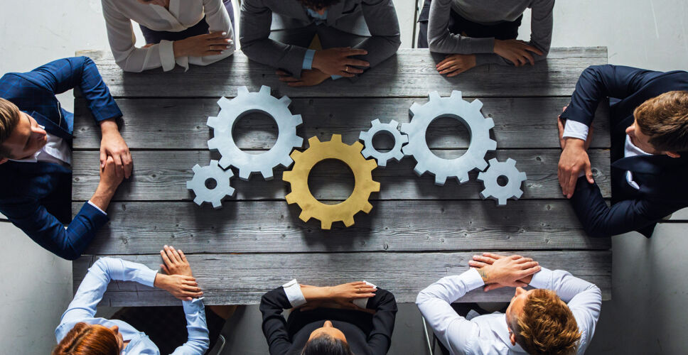 团队合作一群商人在工作场所的顶视图上把银色和金色的齿轮放在桌子上业务工业设备