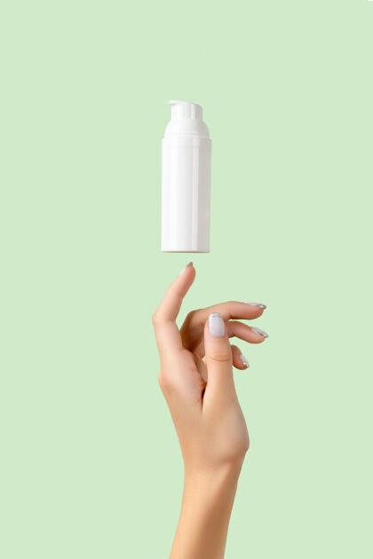 皮肤护理女人的手上有一个淡绿色的白色瓶子霜美容手