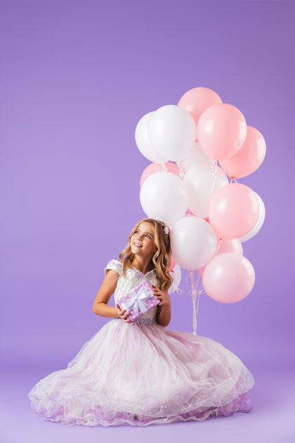裙子穿着公主裙的漂亮小女孩孤零零地坐在紫罗兰色的墙上 手里拿着一堆气球和一个礼盒可爱美丽小