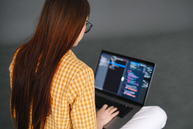 计算机年轻的女手机开发者在电脑上写程序代码程序员的工作笔记本电脑移动数据