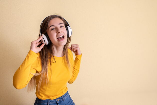 广播戴着耳机在黄色背景上跳舞的年轻女子旋律快乐音乐