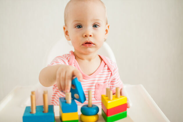 活动时间小女孩玩着一个教育玩具——一个五颜六色的木制玩具金字塔发展精细运动技能和逻辑思考高高质量的照片可爱漂亮小