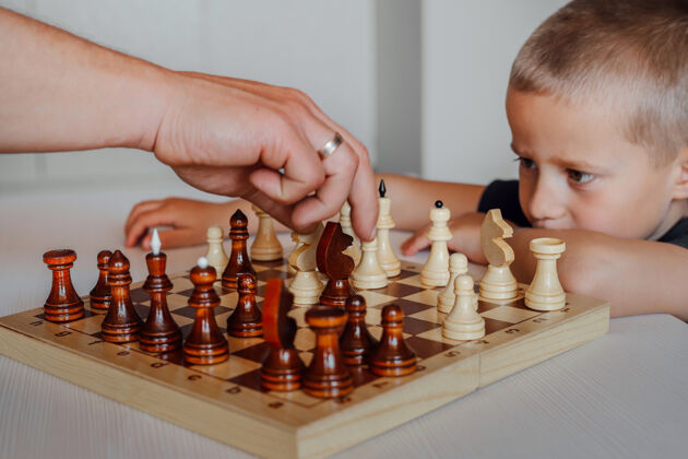 思考棋盘特写 一对父子在玩一个白人小男孩紧紧地盯着他父亲的手游戏专注步骤