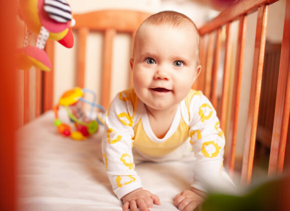 幼儿可爱的白人好奇的小女孩在她舒适的婴儿床上学习爬行的画像肖像年谎言