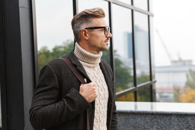 步行30多岁的欧洲男人戴着眼镜 走过城市街道附近的建筑风格成人户外
