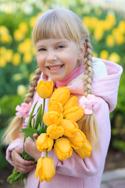 花可爱的小女孩手持一束黄色郁金香 背景是美丽的花朵一个穿粉红色外套的女孩快乐夏天父亲节