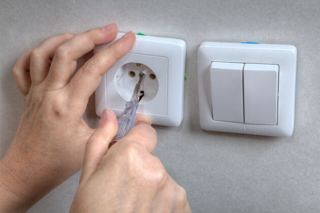 插座电工在用螺丝刀修理电墙插座和灯开关时要用手工具调整电蓝