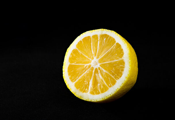 宏观明亮多汁的黄色柠檬在黑色背景上饮食配料甜