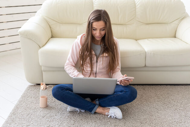 放松技术 自由职业者和人的概念-年轻女子在家工作 她在地板上喝茶 在手机上聊天单身牛仔裤坐着