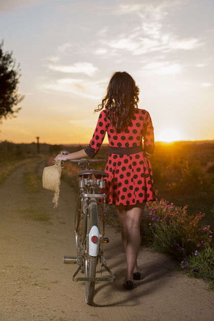 乡村日落时分 骑着自行车在乡间散步的女孩从后面看自行车时尚公园