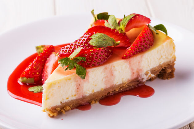 芝士蛋糕美味的自制芝士蛋糕和草莓放在白色的木桌上咖啡馆块派