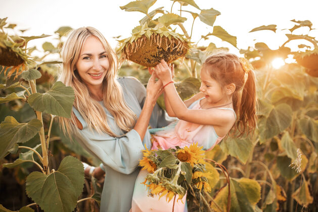 草地年轻漂亮的金发妈妈抱着漂亮的小女儿欢呼年轻自然