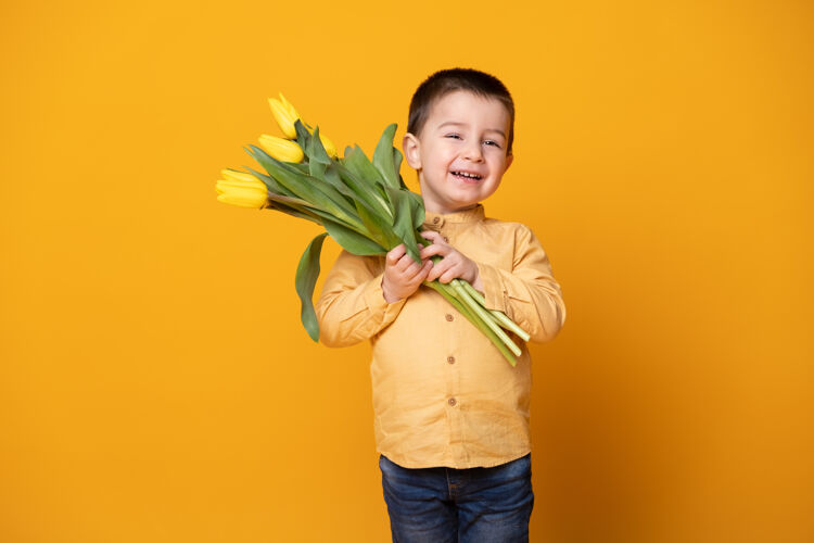 美丽黄色工作室里微笑的小男孩背景欢快郁金香花束快乐的孩子母亲节夏天男孩