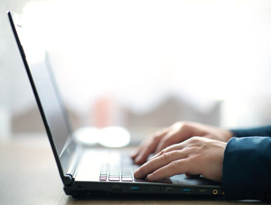 电脑男人的手在笔记本电脑键盘上打字一个在办公室工作的男人在笔记本电脑上写字笔记本电脑选择性集中通信笔记本电脑键盘连接