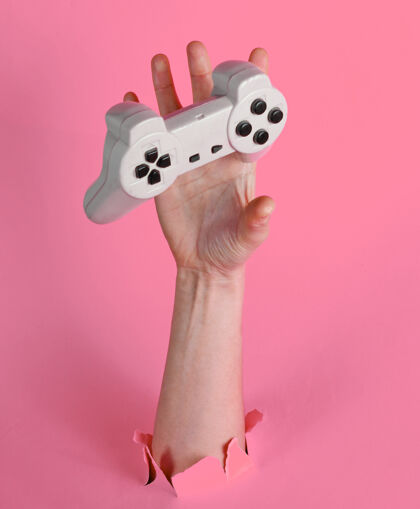 操纵杆母手通过撕破的粉红色抓住游戏板纸简约创意理念游戏游戏控制器