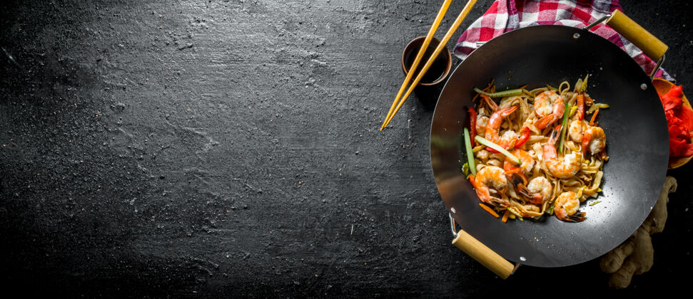 烹饪把乌冬面放在炒锅里 用酱油 筷子和餐巾纸放在黑木桌上传统中国香料