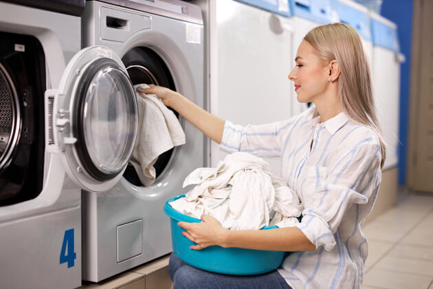 洗衣机洗衣服的女人——从洗衣机里拿出白衣服 放到篮子里 盆地.in洗衣房职责清洁清洁