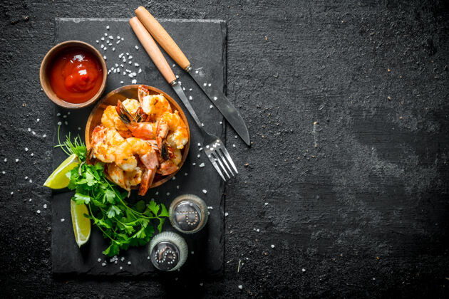 吃黑木桌上放着石板虾 香料 番茄酱和香草蛋白质香料虾