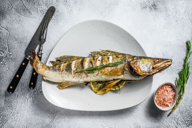 营养烤鱼配香草和柠檬板灰色木制的背景.top查看新鲜鱼片晚餐