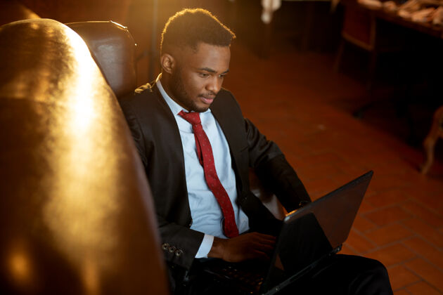 商人帅气的非洲年轻人穿着西装 在室内拿着笔记本电脑互联网信心学生
