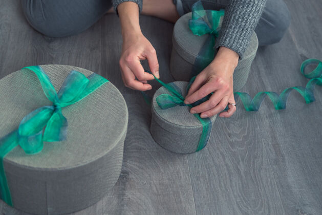 串女人用灰色的圆盒子和绿色的丝带包装礼物丝带绿丝带礼盒