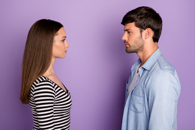 女朋友简介两人情侣男女士站在对面看眼神有冲突情况穿时尚休闲装隔离粉彩紫色墙壁冲突情人约会