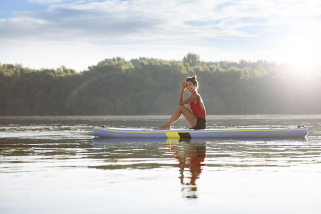 日落阳光明媚的日子里 快乐的女人坐在桨板上宁静夏天大海
