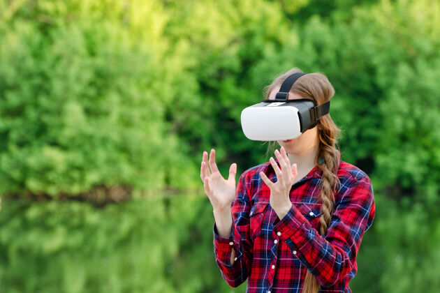 虚拟戴着虚拟现实眼镜的女人 在绿意盎然的背景下 双手握在面前活动模拟Vr
