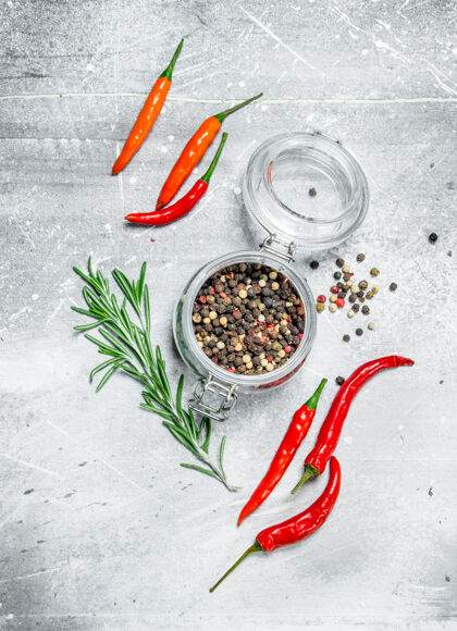 美食放在玻璃罐里的胡椒豆 配上红辣椒和迷迭香放在乡村的桌子上干燥整个胡椒