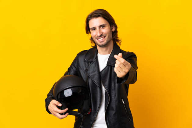 快乐一个戴着摩托车头盔的男人被隔离在黄色的墙上赚钱富有人财务