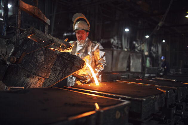 人铸造工人将铁水倒入铸钢 重工业和冶金工艺的模具中熔炉安全钢