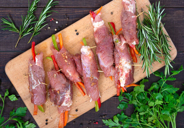新鲜在木板上塞满蔬菜的生肉卷猪肉板生的