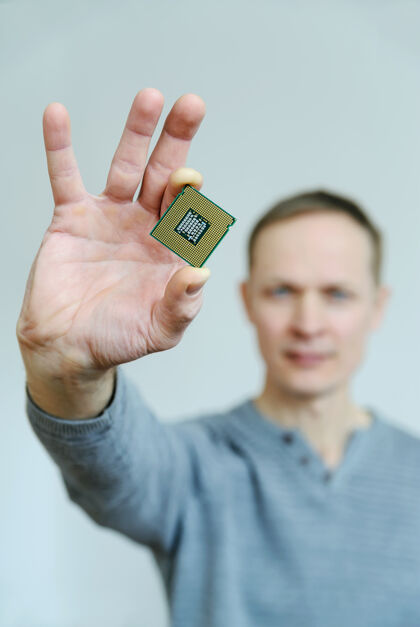 系统处理器在男人的手里一个男人用两个手指夹着一个处理器技术硬件细节
