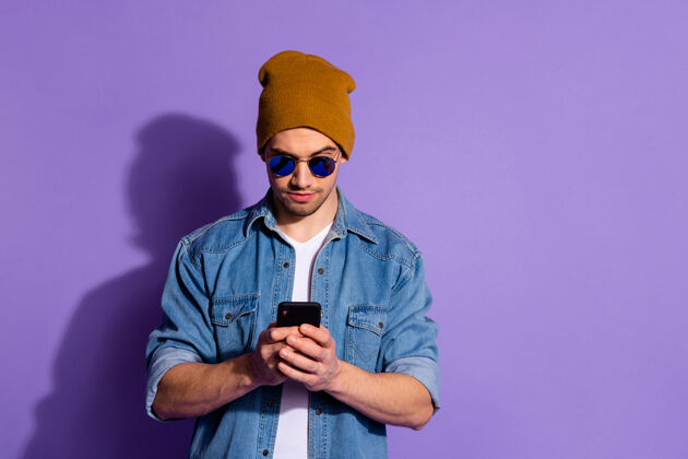 头饰照片中 严肃自信的自由职业者手持电话 双手在互联网上浏览 寻找紫色鲜艳背景下孤立的新信息太阳镜信息衬衫
