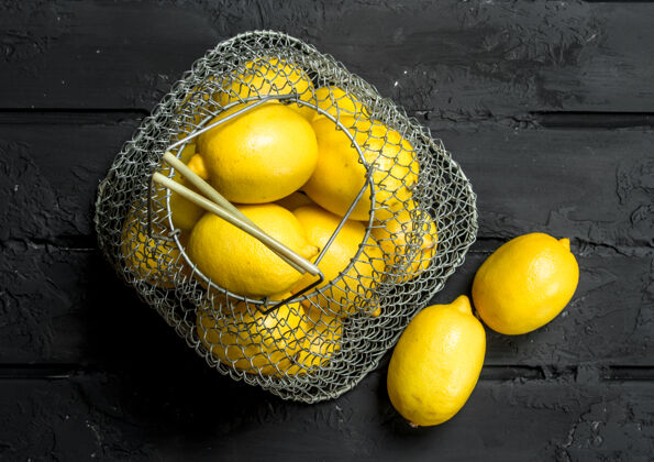 顶部把新鲜的柠檬放在铁篮子里放在乡下的桌子上果汁酸营养