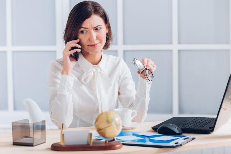 工作漂亮的女商人在办公室打电话和办公桌边工作计算机坐着企业家