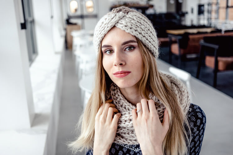 年轻美丽可爱的女人 戴着冬天的针织帽子和围巾在咖啡馆的背景上漂亮肖像针织