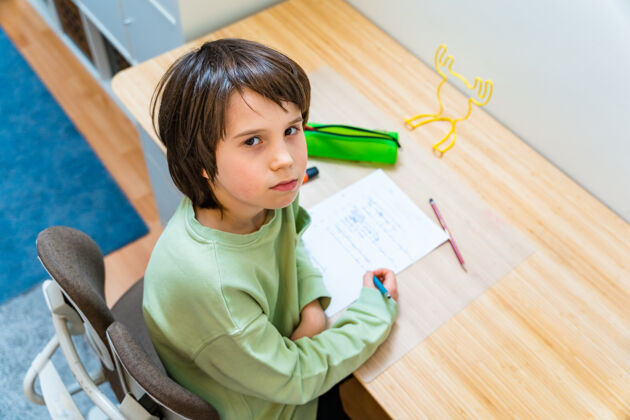 学习小男孩坐在桌子旁做作业回家累了让孩子不安的写作练习家庭教育铅笔房子写作