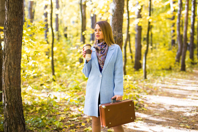 叶子秋天 自然和人的概念-年轻漂亮的女人在蓝色外套举行一杯咖啡时尚十月女性