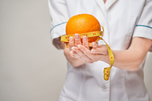 白种人营养师医生健康的生活方式理念-拿着橘子水果和卷尺水果医生制服