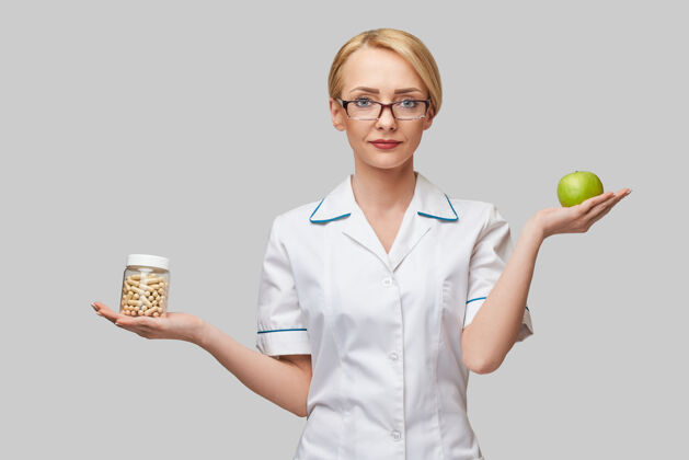 胶囊营养师医生健康的生活方式概念-持有有机新鲜青苹果和维生素胶囊罐有机工作健康的生活方式