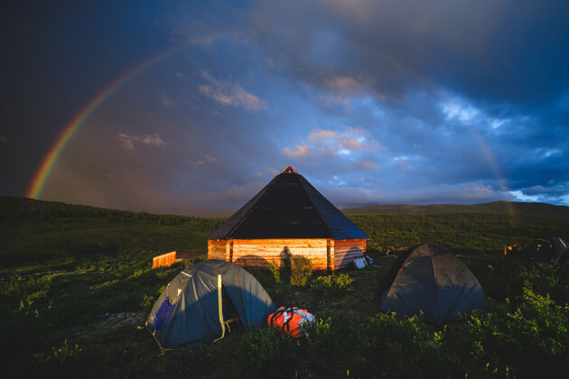 西伯利亚所有传统的阿尔泰房子和旅游帐篷下的彩虹穹顶在奥古斯基地区的阿尔泰共和国 俄罗斯山满景观