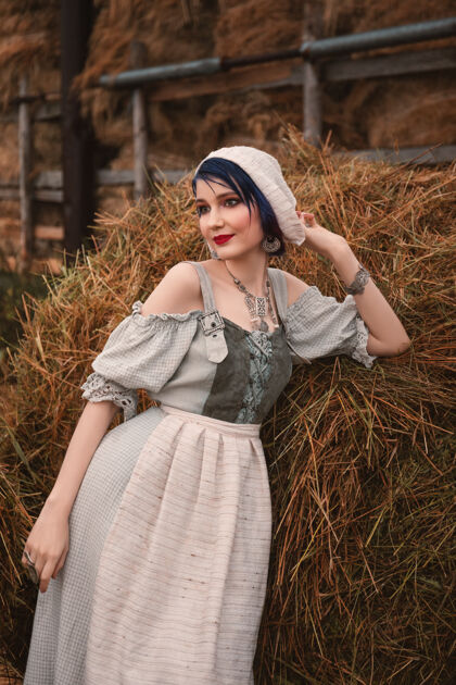 农业身着传统巴伐利亚服装的美丽年轻女子站在农场的干草堆旁干草高加索服装