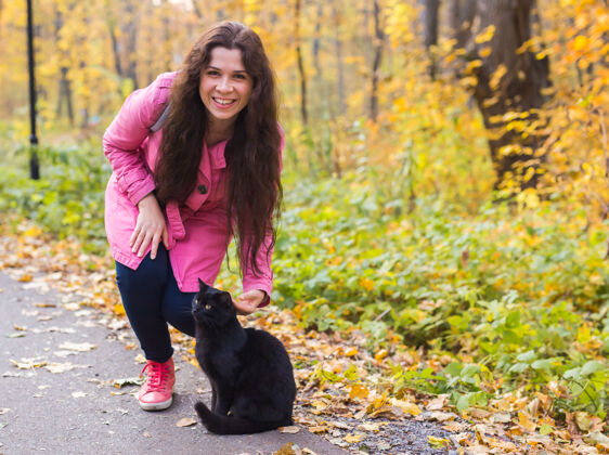 快乐秋天公园里的年轻女人和一只黑猫秋天夫妻女孩
