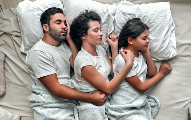 女人一家人睡在舒适的床上休息家庭男人