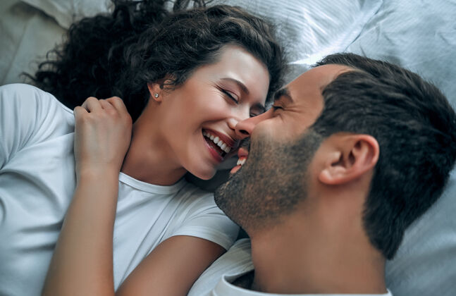 微笑美丽的情侣在床上接吻在一起房间性